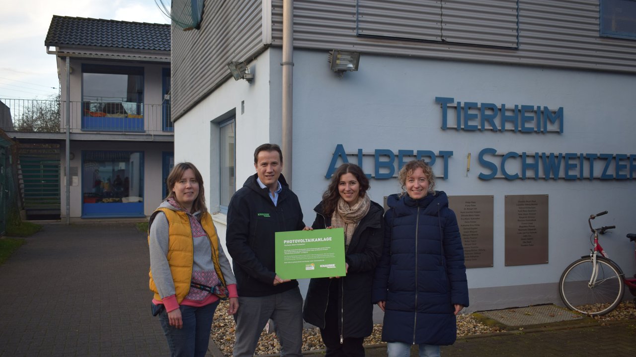 Vier Personen stehen vor dem Tierheim Albert Schweitzer, eine Person hält ein grünes Schild mit Text.