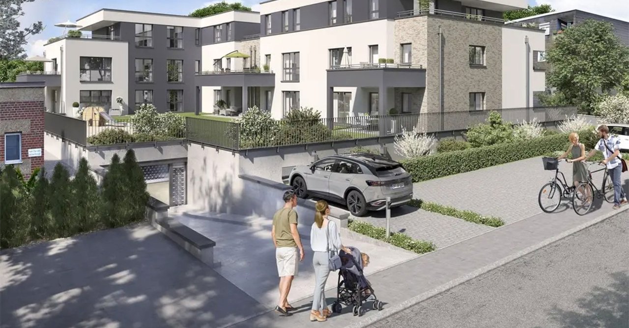 Familie mit Kleinkind spaziert an moderner Wohnanlage mit Stellplätzen, Garten und Tiefgaragenzufahrt vorbei.